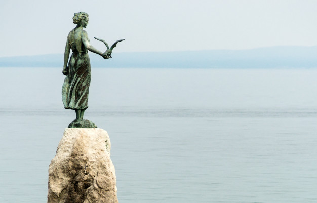 maiden-girl-holding-seagull-facing-sea-statue-rocks-opatija_105811-116